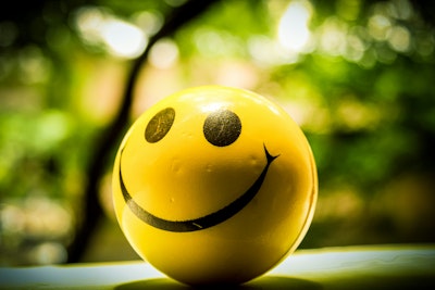 A smiley face on a yellow ball, against a sunny background 