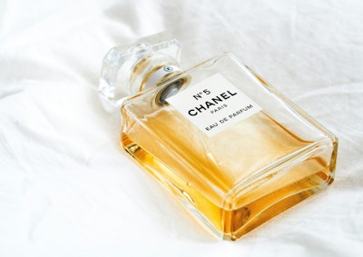 A Chanel No. 5 bottle on a white bedsheet 