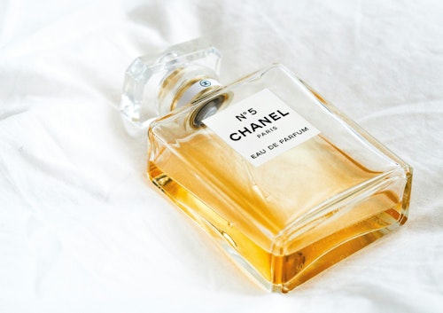 A Chanel No. 5 bottle on a white bedsheet 