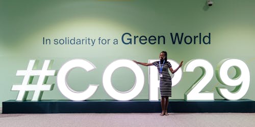 A delegate stands in front of a logo for COP29 A delegate stands in front of a logo for COP29