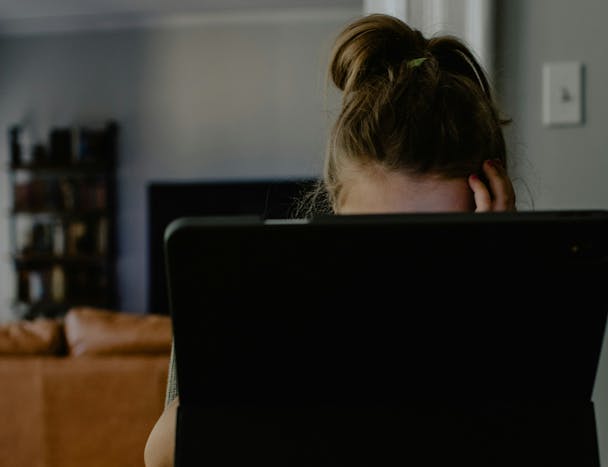 A woman with her head in her hands sits behind an ipad A woman with her head in her hands sits behind an ipad