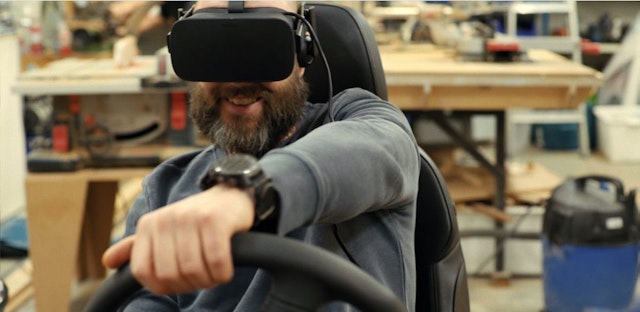 A man steering the wheel of a VR driving experience.