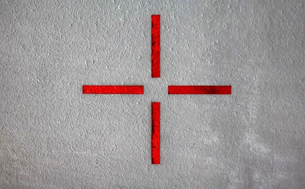 Four red lines mark a target on a grey wall