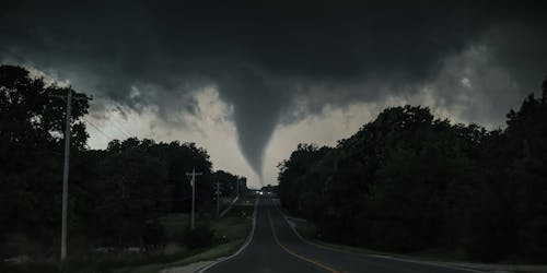 A tornado on the horizon at the end of a road A tornado on the horizon at the end of a road