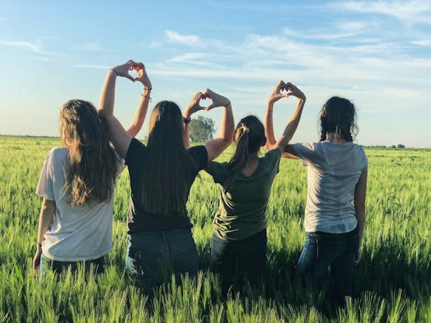 People stand in a row in a field making love hearts by joining their hands People stand in a row in a field making love hearts by joining their hands