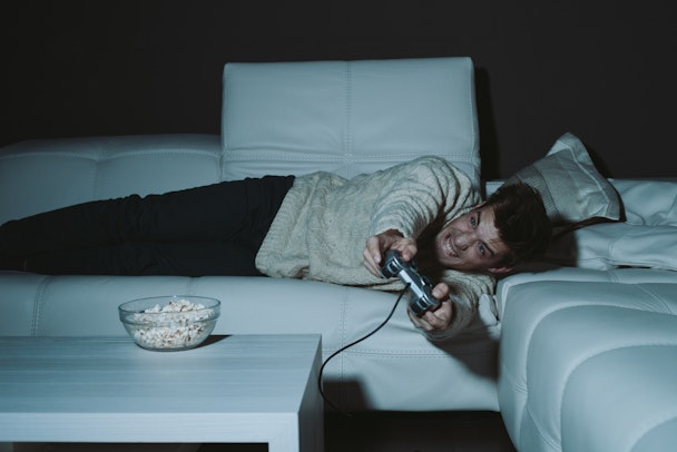 Man lying on couch playing video games