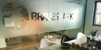 Photograph of an office space with a frosted glass divider showing the Brave Spark logo