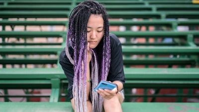 Woman sits on bleachers reading her phone