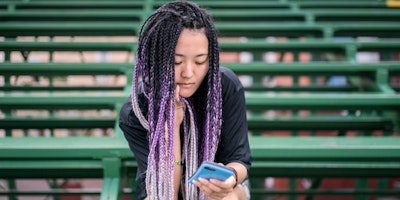Woman sits on bleachers reading her phone