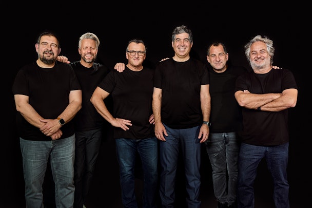 Gut and Globant's executive teams, standing in front of a black background wearing black T shirts