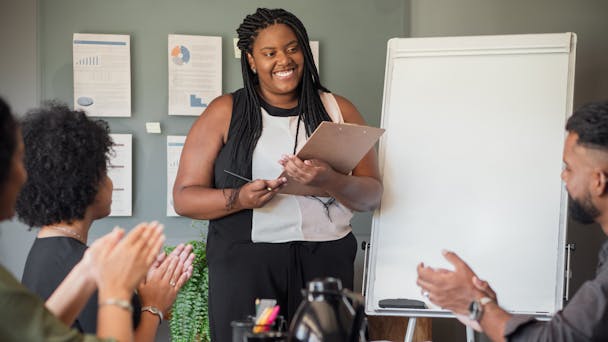 A woman in a business pitch addressing an audience in a boardroom A woman in a business pitch addressing an audience in a boardroom