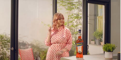 woman standing next to a bottle of aperol woman standing next to a bottle of aperol