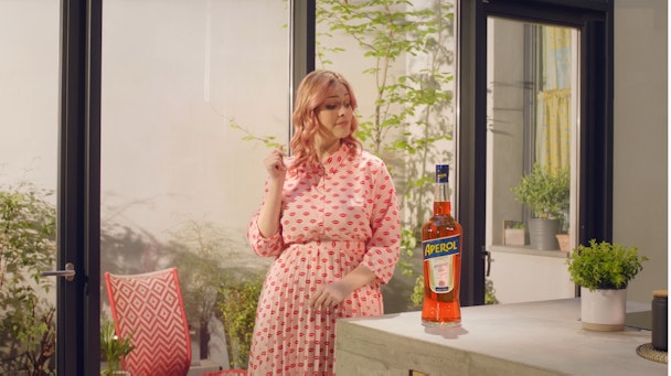 woman standing next to a bottle of aperol