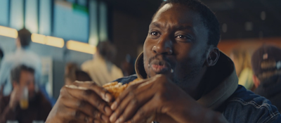 A man eating a Burger King whopper in a restaurant