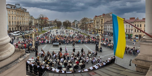 The Ukrainian flag flies above a concert orchestra playing outdoors in Lviv