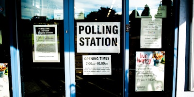 A stock photo showing a sign hung on a glass door showing a temporary polling station in the UK