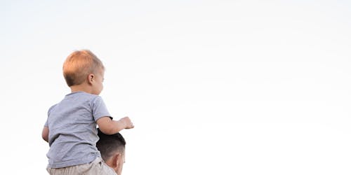 a child sitting on its parent's shoulders a child sitting on its parent's shoulders
