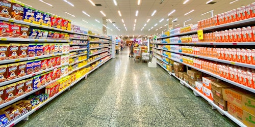 Supermarket aisles showing colourful goods on shelves, with a trolley in the distance