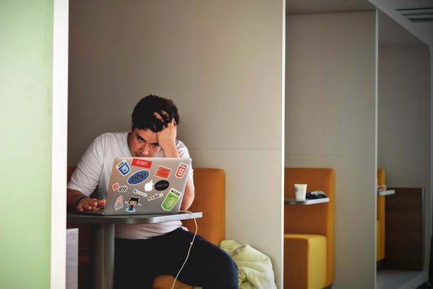 A man sitting at a desk pushing his fingers through his hair, looking stressed A man sitting at a desk pushing his fingers through his hair, looking stressed