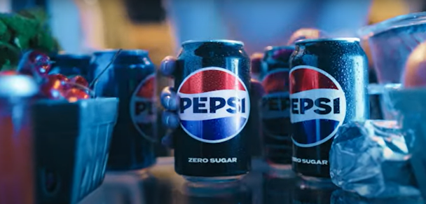 A can of Pepsi, seen from the back of a fridge, being grabbed by a hand