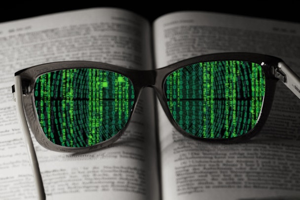 A pair of glasses lying on a book, through the lenses of which you can see lines of code instead of written text