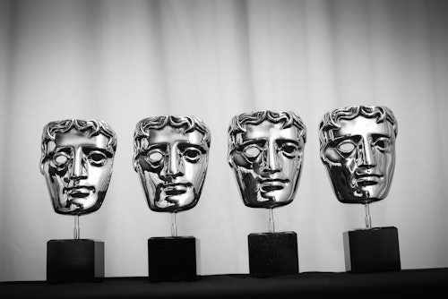 A row of BAFTA trophies against a plain background