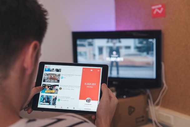 A man watching YouTube on both his tablet and the TV simultaneously