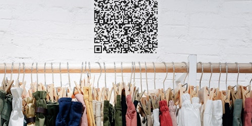A QR code on the wall over a clothes rack
