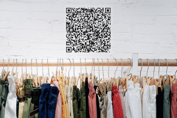 A QR code on the wall over a clothes rack