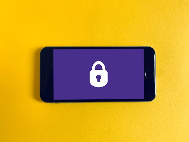 iphone screen with a lock image, sitting on a yellow bakground