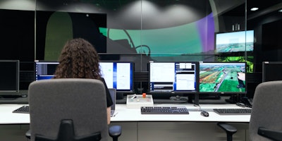 woman sitting at desk in office with multiple screens