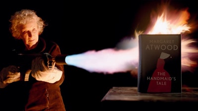 Margaret Atwood firing a flame thrower at her book, The Handmaid’s Tale