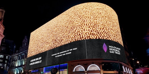 A large outdoor digital ad screen showing thousands of candles being lit