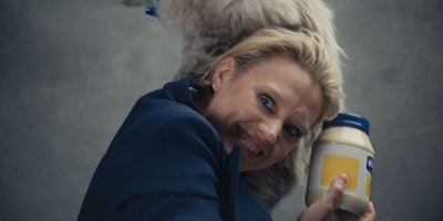 Kate McKinnon with a cat on her shoulder and a jar of mayonaise in her hand