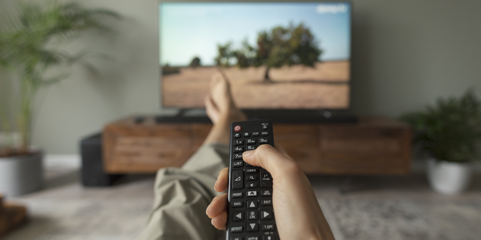 Woman holding remote control pointing it at TV
