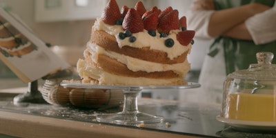 A stacked cream cake begins to collapse to one side.