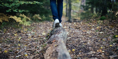 A man walking along a fallen log.
