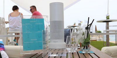 A smart speaker sits on a kitchen table.