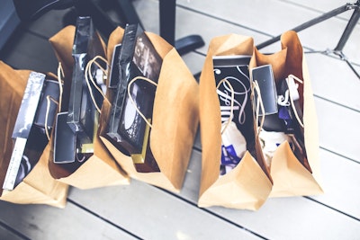 A row of paper shopping bags, full of purchases.
