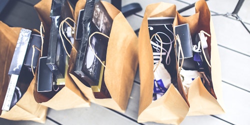 A row of paper shopping bags, full of purchases.