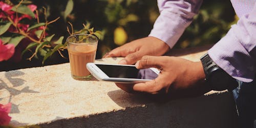 A man uses a mobile phone while enjoying a coffee. A man uses a mobile phone while enjoying a coffee.