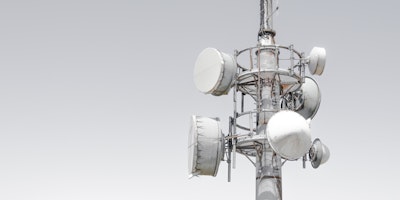Mobile phone mast with several reception dishes attached.