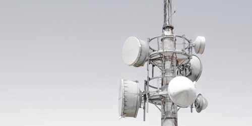 Mobile phone mast with several reception dishes attached.