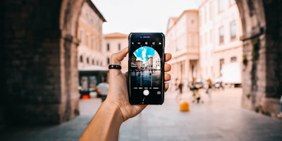 A smartphone capturing an image of an ornate arch.