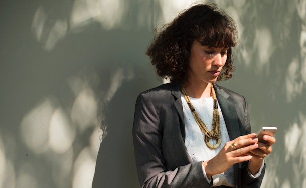 A smartly-dressed woman looks at her smartphone.