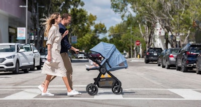 Mother and father push baby in a Stokke stroller.