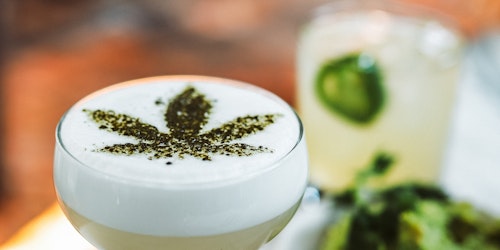 A cocktail with a green cannabis insignia sprinkled on top.