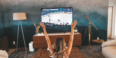 Woman cheering while watching a hockey game on TV in her living room