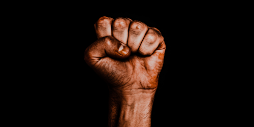 Black hand in a fist against a black background