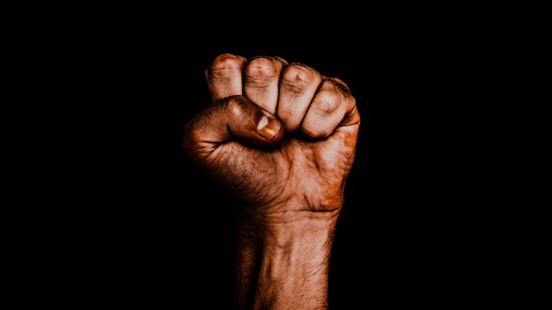 Black hand in a fist against a black background